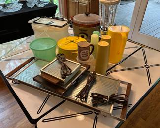 Vintage mid-century enamel-top drop-leaf kitchen table with chrome hairpin legs, paired with retro serving trays, small appliances, and kitchenware.