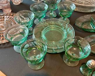 Collection of green depression glass including bowls, plates, and stemware.