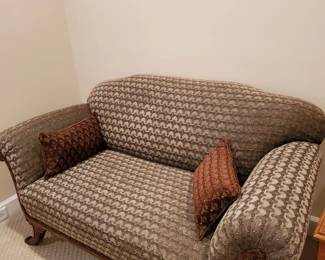 Sofa: classic rolled arms with curved back Decorative wood trim with carved detailing Neutral patterned upholstery for versatility Comfortable, tailored seating with accent pillows  A stylish and comfortable piece, perfect for adding warmth and traditional charm to a living room, study, or sitting area.