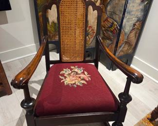 Decorative, traditional armchair, combines carved wood, cane work, and embroidered upholstery for a classic aesthetic.