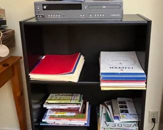 black bookcase with paper products, desk lamp & candle