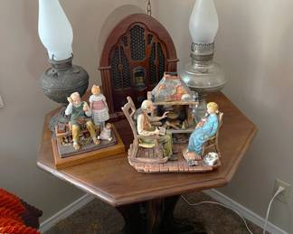 There is a classic-styled radio on the table, as well as two more oil lamps, and two figurine-based scenes.