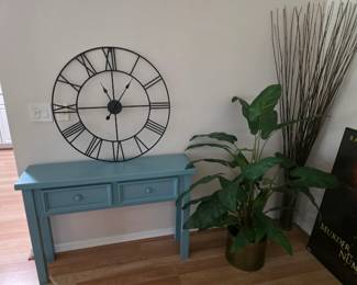 Large wall clock, artificial plant, table