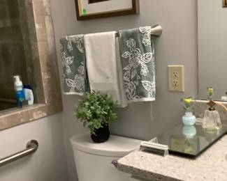 Towels, artificial plant and on sink are two Vintage perfume bottles.