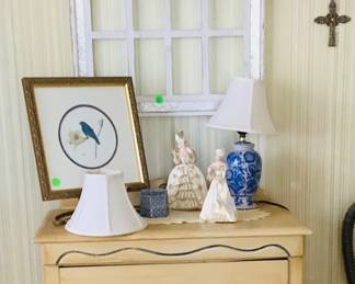 A hand painted chest, hanging above is a white window frame with wreath.