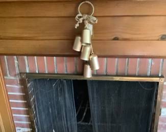 Set of gold bells hanging from fireplace.
