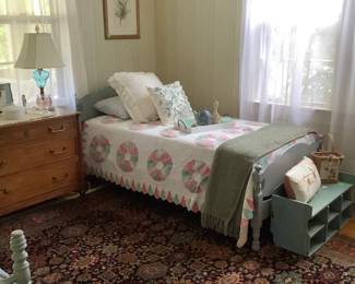 The other twin bed painted in Irish blue with a quilt spread with green throw and decorative pillows.
