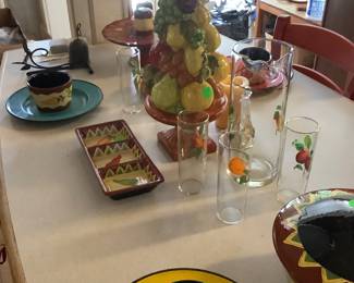 Some beautiful, colorful pottery, along with a cake stand, 60’s pitcher with glasses that have different fruit patterns.