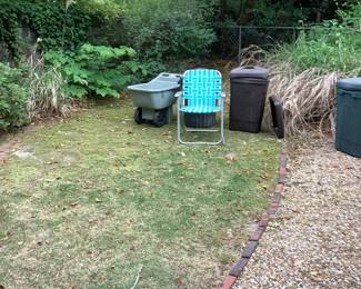 Large black thrash cans, folding chairs, wheel carrier.