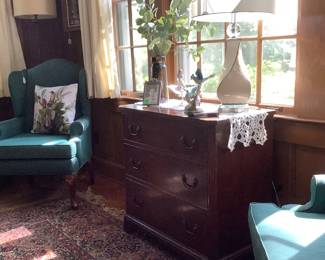 Sitting between the chairs are a mahogany chest with several accessories and beautiful  lamps.  One is sitting on unusual  3 tier end tables.