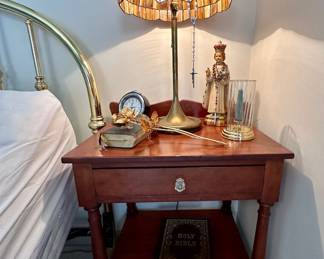 Antique cherry nightstand with a vintage stained glass and brass lamp.