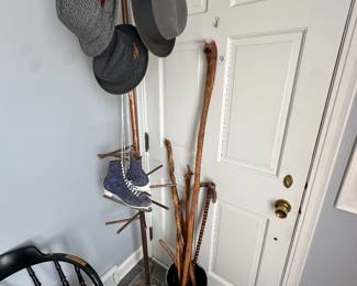 Hey duty metal coat rack with mens hats and carved walking sticks.