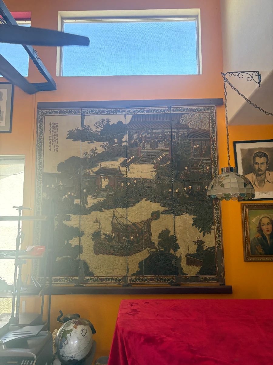 A stunning and rare 4-panel folding screen featuring a detailed painted scene of figures, boats, pagodas, and landscapes with Chinese calligraphy inscription. Dark lacquered wood frame. Diplomat provenance — brought to the U.S. from East Asia. Statement piece for any home. Approx. 6' tall x 6' wide fully open.