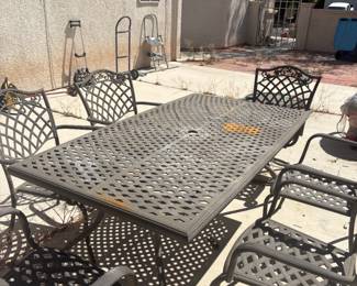 Cast Aluminum Patio Dining Set — Table + 6 Chairs Heavy cast aluminum outdoor dining set in classic lattice design with ornate scrollwork. Large rectangular table with umbrella hole, six matching arm chairs. Durable and substantial — built to last. Some surface rust present, priced accordingly. Must be able to load and transport same day.