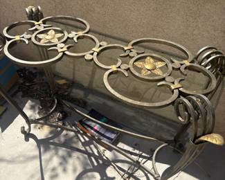 Elegant decorative console or sofa table with wrought iron frame in antique silver/gold tone. Features two circular medallion panels with gold star and flower motifs, scrollwork legs, and a glass top shelf in perfect condition. Suitable for entryway, living room, or covered outdoor space. Stunning statement piece.