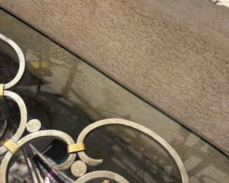 Elegant decorative console or sofa table with wrought iron frame in antique silver/gold tone. Features two circular medallion panels with gold star and flower motifs, scrollwork legs, and a glass top shelf in perfect condition. Suitable for entryway, living room, or covered outdoor space. Stunning statement piece.