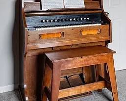 This item is an antique pump organ or reed organ, a type of harmonium that uses free reeds to produce sound