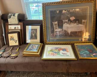 Variety of artwork, originals and prints sitting on a futon