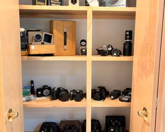 A cabinet full of high quality cameras and a vintage projector