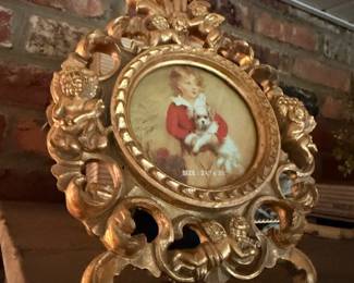 Ornate gilt oval framed portrait of child with dog