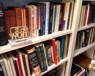 Bookshelves of assorted hardcover books and cookbooks