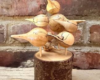 Carved wood folk art shorebird decoys grouped on log stand