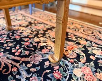 Carved table leg on floral Oriental rug