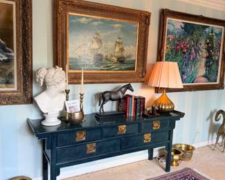 Black console table with bust and ship paintings