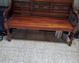 Late 20th-century hand carved Teak decorative bench featuring X-shaped back and slated seat design.