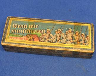 Lot 47. M. Hohner "Wenn wir Marschieren" (When we March) 80-hole double-sided tremolo harmonica in the box. The back cover of the harmonica is loose. The box has been taped and has interesting graphics of pre-WWII German soldiers
