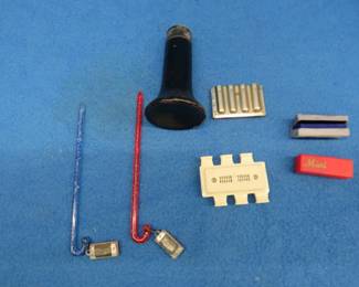 Lot 168. Pitchpipes and miniature harmonicas and more: Guitar pitch pipe. Violin pitch pipe. Two 1 3/4" empty boxes. Two 3/4" 2-hole harmonicas on candy canes. Poor or no sound. Wooden QRS DeVry piece?