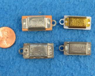 Lot 166. Four miniature 2-hole harmonica charms: Queen 1" with good sound. Robin 1" with no sound. Atom 7/8" with good sound. Medal 7/8" with good sound.