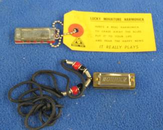 Lot 238. Two miniature harmonicas: Hohner like-new 1 3/8" 4-hole advertising harmonica from the Country Music Hall of Fame on a beaded necklace. Sounds great. Medal 1 3/8" Lucky Miniature Harmonica. Blow only.