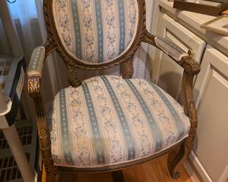 Louis XVI style armchair featuring a carved giltwood frame and floral striped upholstery.