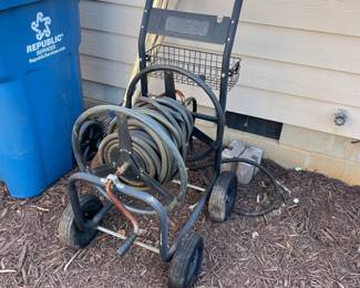 T133 - $30. Hose reel on metal rolling cart. Needs air in the tires. 