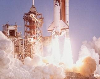 This lot features a collectible vintage NASA photograph depicting a Space Shuttle launch. Signed by NASA associate and measures on backer, 20” H x 16” W.