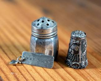 This lot features a collection of sterling silver items including a thimble, pendant, and a salt/pepper shaker.