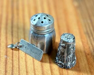 This lot features a collection of sterling silver items including a thimble, pendant, and a salt/pepper shaker.