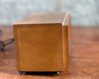 Seth Thomas vintage wooden flip clock featuring a natural woodgrain exterior with a silver-tone faceplate. Displays time using a rotating flip mechanism. Includes an attached electric cord for operation. Minimal signs of wear are visible consistent with age. Tested and in working condition.