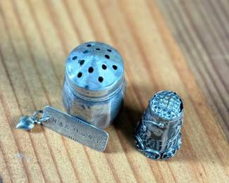 This lot features a collection of sterling silver items including a thimble, pendant, and a salt/pepper shaker.
