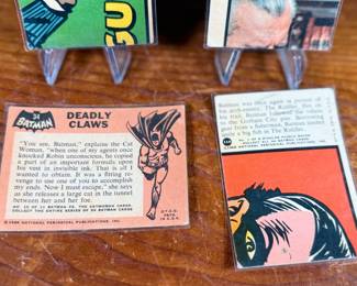 Vintage Batman trading cards, featuring original artwork and comic illustrations. Cards include storylines and engaging captions on the reverse side. Produced by National Periodical Publications, Inc., circa 1960s. Cards are displayed on stands; conditions appear fair with signs of handling and age.