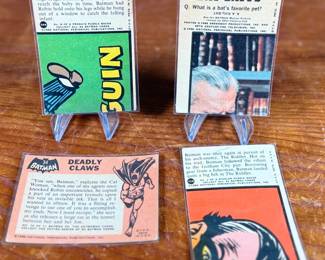 Vintage Batman trading cards, featuring original artwork and comic illustrations. Cards include storylines and engaging captions on the reverse side. Produced by National Periodical Publications, Inc., circa 1960s. Cards are displayed on stands; conditions appear fair with signs of handling and age.