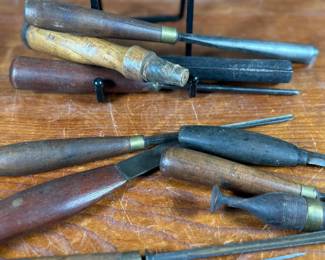 Vintage woodworking tools, including chisels and gouges with wooden handles. Some tools are marked “Buck Bros, ” known for quality craftsmanship. Handles exhibit wear consistent with age and use. The lot includes a variety of sizes and types for woodworking projects or collection purposes. Condition varies, with some minor rust and patina on metal components.