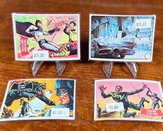Vintage Batman trading cards, featuring original artwork and comic illustrations. Cards include storylines and engaging captions on the reverse side. Produced by National Periodical Publications, Inc., circa 1960s. Cards are displayed on stands; conditions appear fair with signs of handling and age.