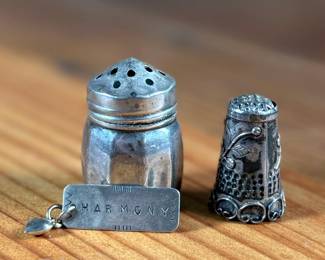 This lot features a collection of sterling silver items including a thimble, pendant, and a salt/pepper shaker.