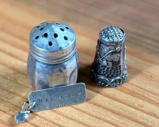This lot features a collection of sterling silver items including a thimble, pendant, and a salt/pepper shaker.