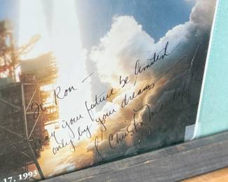 This lot features a curated collection of space memorabilia held and displayed in a wooden frame. Includes an autograph from Christa McAuliffe and much more. This piece measures in frame, 22.5” H x 18.75” W.