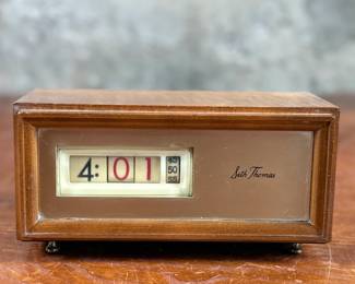 Seth Thomas vintage wooden flip clock featuring a natural woodgrain exterior with a silver-tone faceplate. Displays time using a rotating flip mechanism. Includes an attached electric cord for operation. Minimal signs of wear are visible consistent with age. Tested and in working condition.