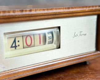 Seth Thomas vintage wooden flip clock featuring a natural woodgrain exterior with a silver-tone faceplate. Displays time using a rotating flip mechanism. Includes an attached electric cord for operation. Minimal signs of wear are visible consistent with age. Tested and in working condition.