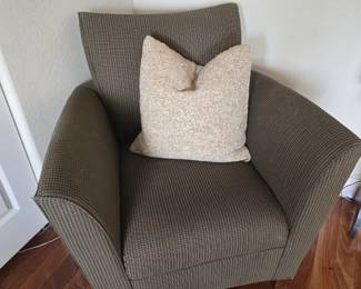 Upholstered green chair with several awesome pillows throughout